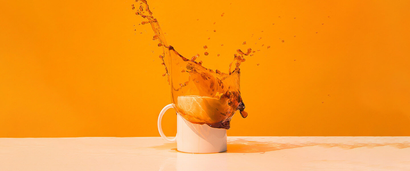 coffee mug with coffee splash against orange background