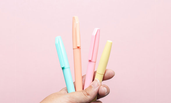 Aruga Website_Blog Images_Proofreading Hand holding group of pens against pink background