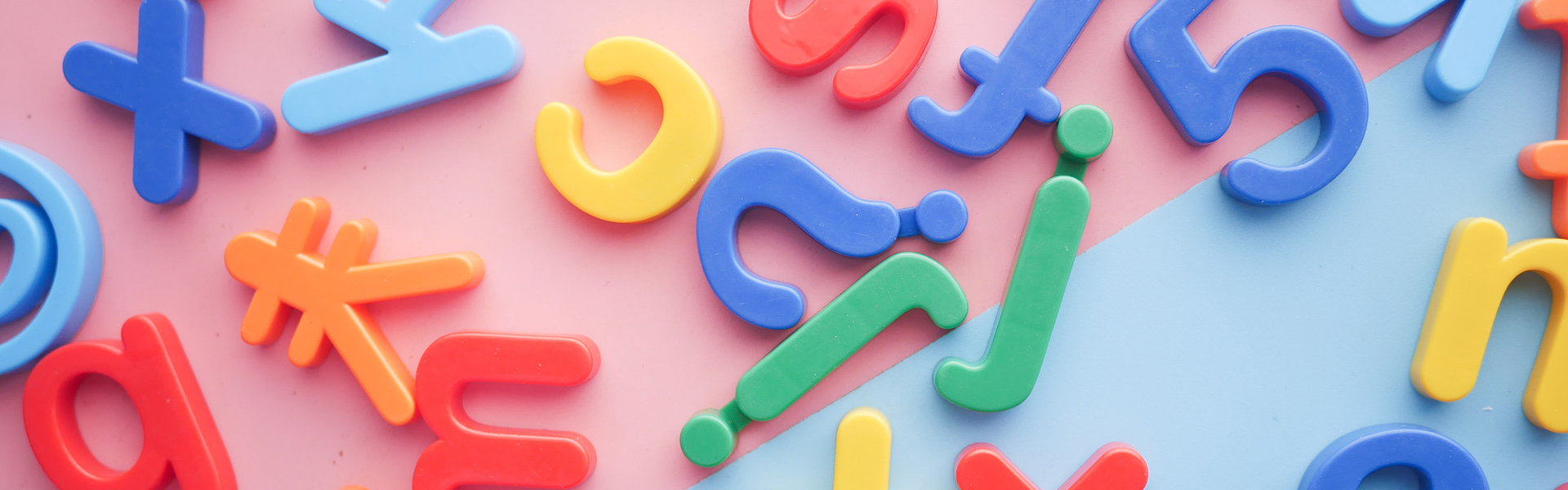 Brightly coloured plastic fridge letters on a pink background
