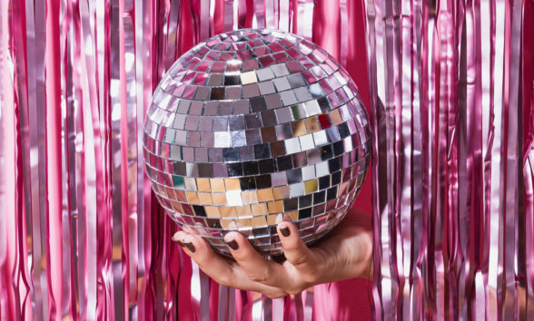 13 Campaigns New Hand holding mirrorball against pink tinsel background
