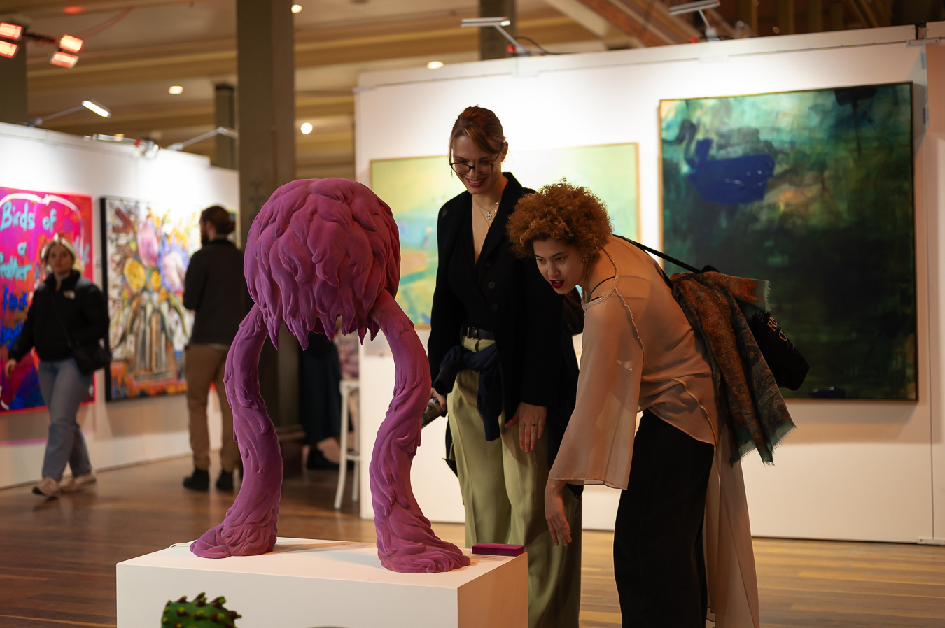 Two people interacting with art exhibiting at Affordable Art Fair Melbourne – a purple sculpture. Person on left is leaning in and pointing.