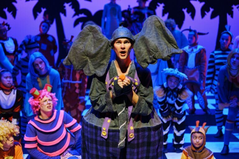 Stage School Australia, Seussical the Musical Boy wearing an elephant suit depicting Horton from Dr Seuss. Background is lit in a dark blue light, his expression is shocked.