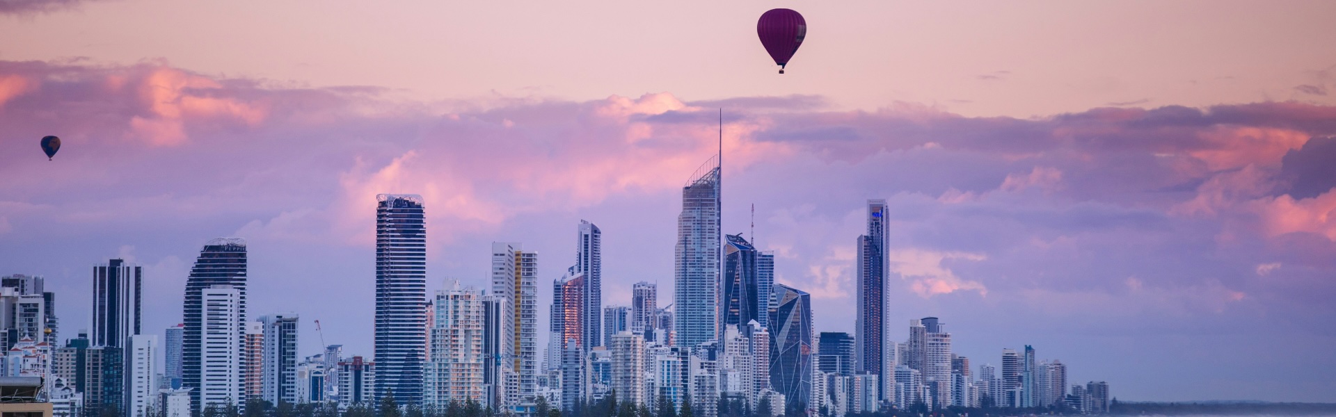 Image of Brisbane skyline. Purple sunset with hot air balloon in sky.