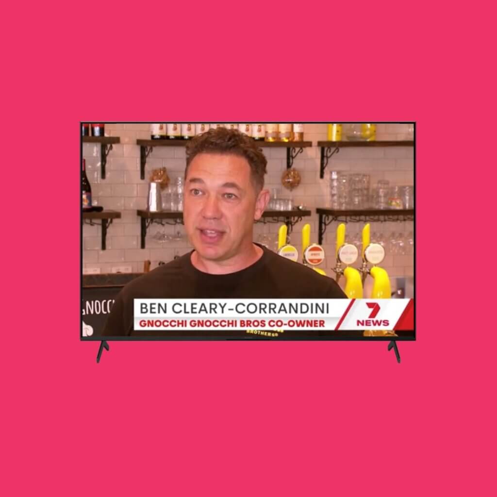 Bright pink background with TV in screen in centre featuring LMBA finalist Gnocchi Gnocchi Brothers interviewed by 7 News Brisbane.