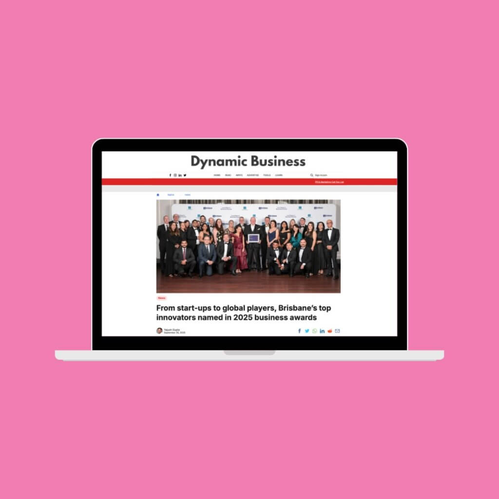 Soft pink background with laptop screen within. Screen shows Dynamic Business article with an image of the winners.